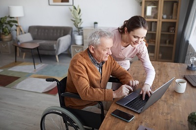 Picture of a Carer helping an elderly person working on a laptop
